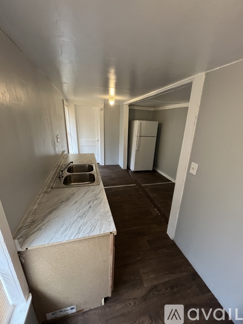 A kitchen with a sink and a refrigerator in a room with white walls.