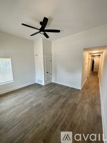A room with a ceiling fan and wooden flooring.
