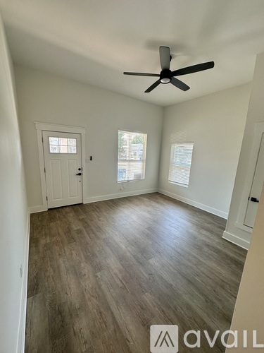 A room with a ceiling fan and wooden flooring.