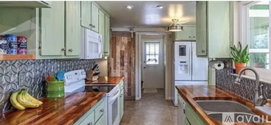 A kitchen with green cabinets and a wooden countertop.