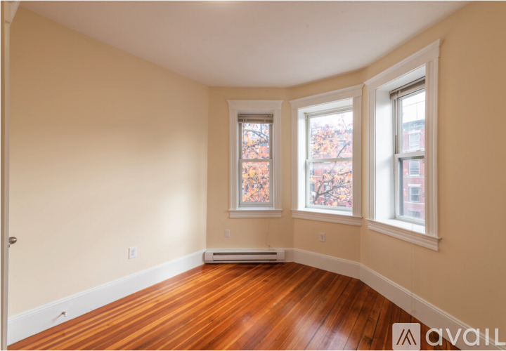 A room with wooden floors and three windows.