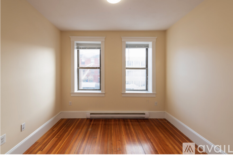 A room with two windows and wooden floors.