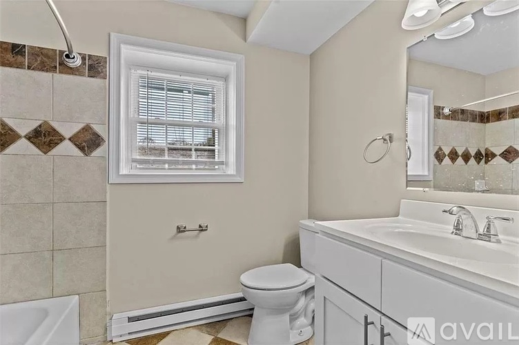 A bathroom with a toilet, sink, and a window.