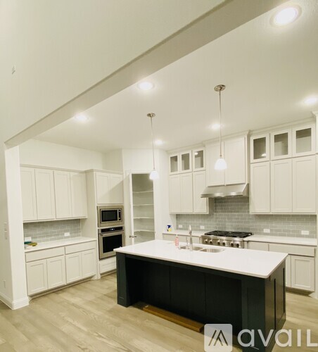 A kitchen with white cabinets and a black island.