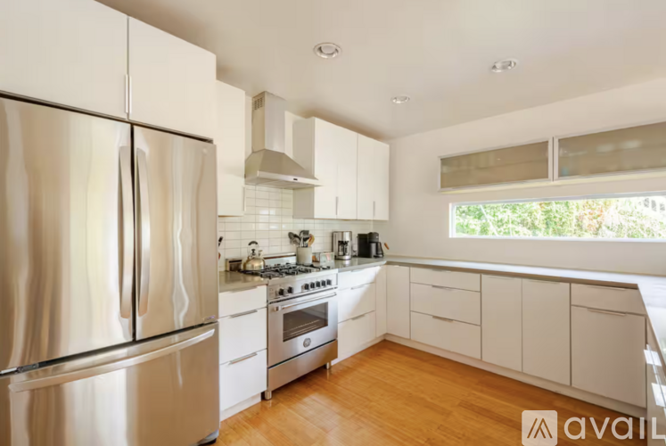A modern kitchen with a stainless steel refrigerator and wooden floors.