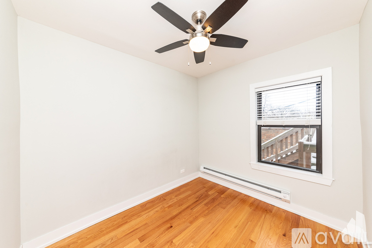 A room with a ceiling fan and a window overlooking a balcony.