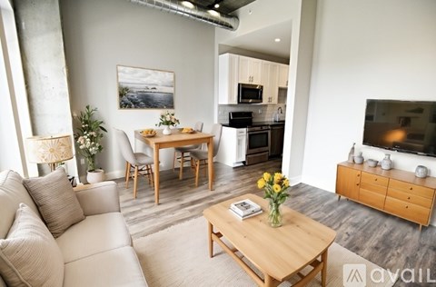 A living room with a white couch, a wooden coffee table, and a painting on the wall.