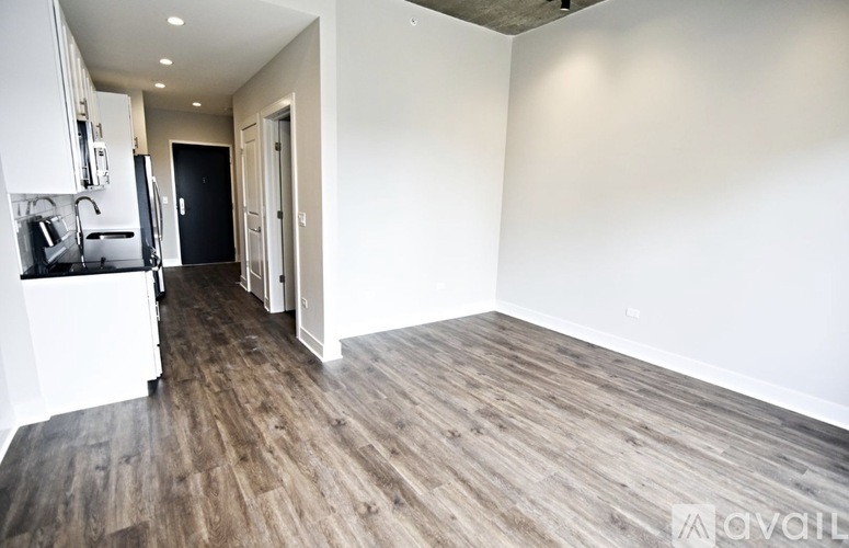 A spacious room with wooden flooring and white walls.