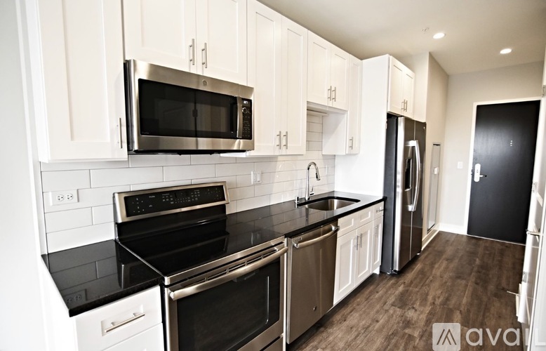 A kitchen with black countertops and stainless steel appliances.