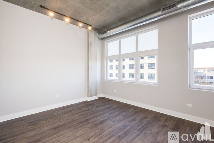 A room with wooden floors and a large window with a view of buildings outside.