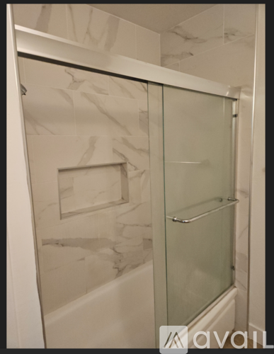 A bathroom with a glass shower door and a marble wall.