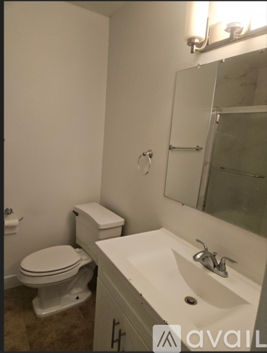A bathroom with a toilet, sink and mirror.