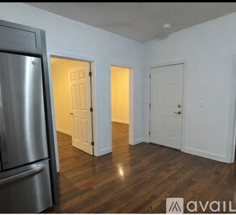 A kitchen area with a refrigerator and a hallway with doors.