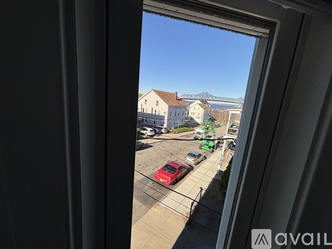 A view from a window looking out at a parking lot and a building.