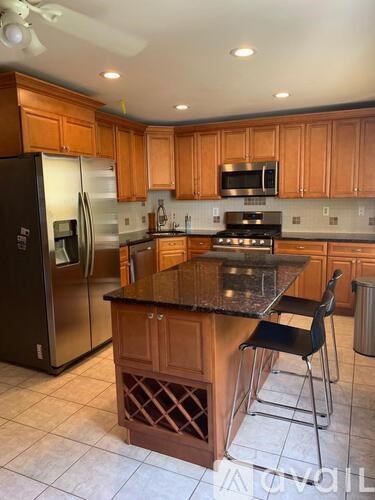 A kitchen with wooden cabinets and a black fridge.