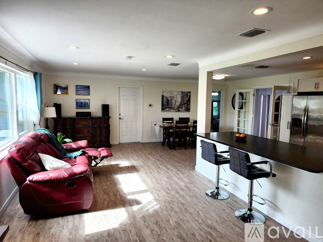 A living room with a red chair and a bar area.
