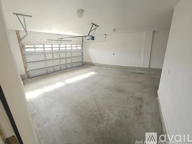 A large empty room with a garage door in the middle.