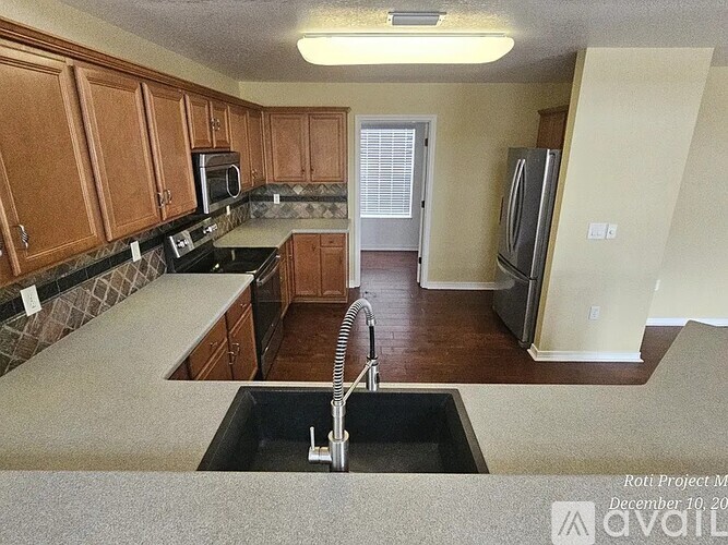 A kitchen with wooden cabinets and a black counter top.