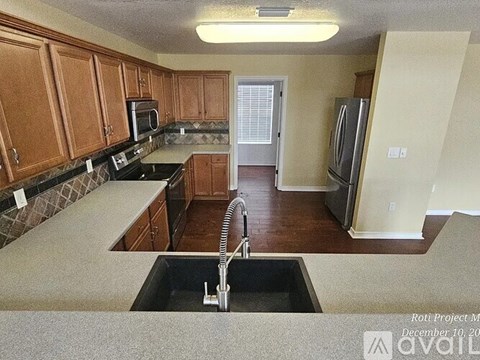 A kitchen with wooden cabinets and a black counter top.