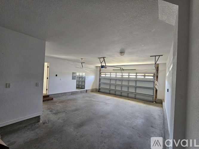 A spacious garage with a white wall and a closed metal gate.