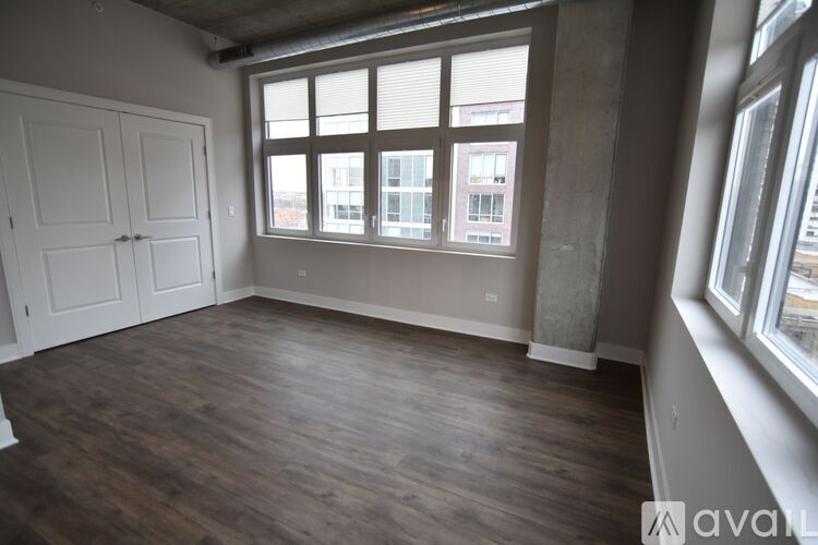 A room with wooden floors and a large window with a view of a building.