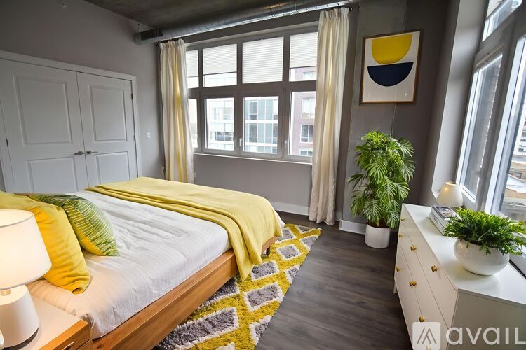A bedroom with a bed, a nightstand, and a window with a view of the city.