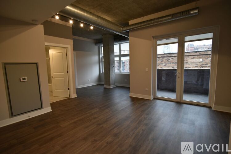 A spacious room with wooden floors and large windows.