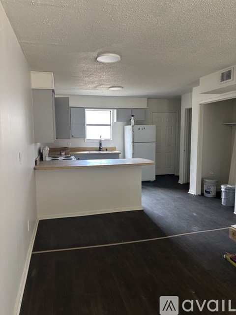 A kitchen with white cabinets and a white fridge is available for rent.