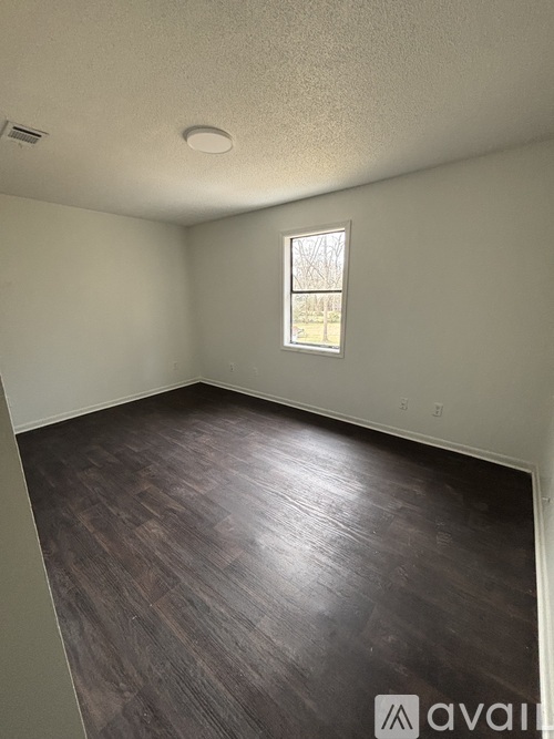 A room with a window and wooden flooring.