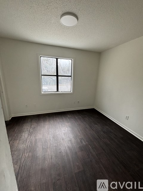 A room with a window and wooden flooring.
