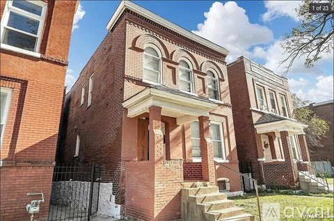 A red brick house with a black gate in front.