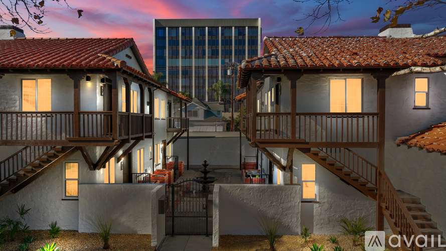 A modern house with a glass building in the background is available for purchase.