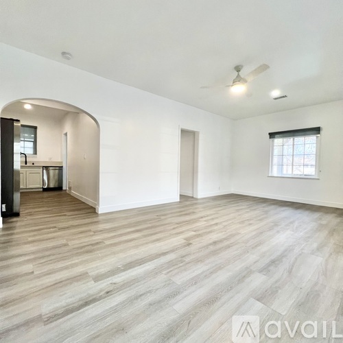 A spacious room with wooden flooring and a ceiling fan.
