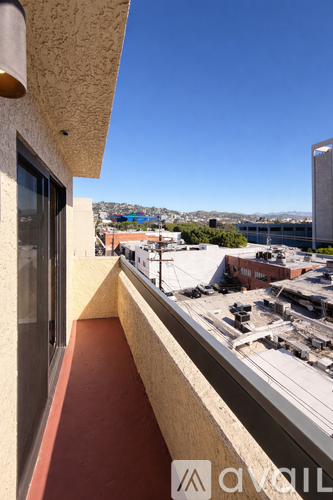 A balcony with a view of a parking lot and buildings.