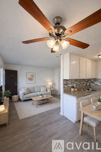 A modern living room with a ceiling fan and a dining area.