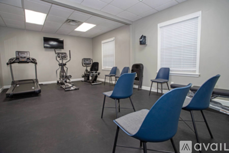 A gym room with exercise equipment and blue chairs.