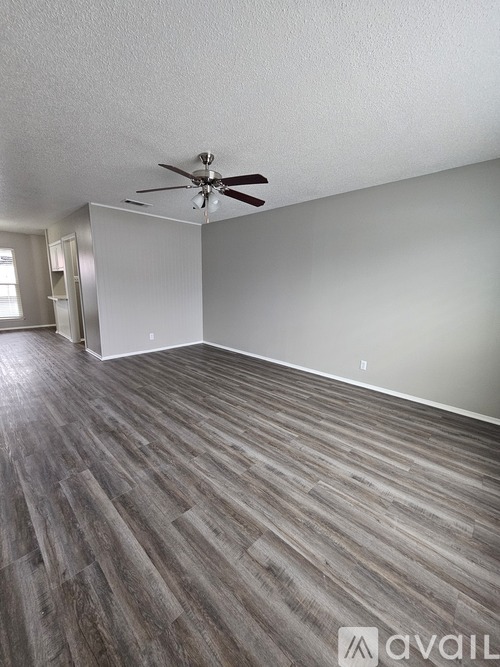 A room with a ceiling fan and wood flooring.