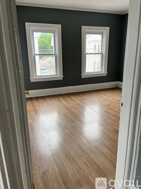 A room with two windows and wooden flooring.