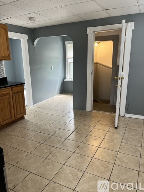 A kitchen with a refrigerator, cabinets, and a door leading to another room.