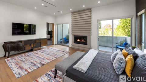 A modern bedroom with a large bed and a fireplace.