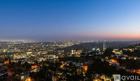 A cityscape at night with buildings illuminated and a clear sky.
