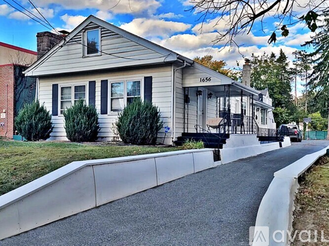 A house numbered 1656 is situated on a street with a sidewalk.