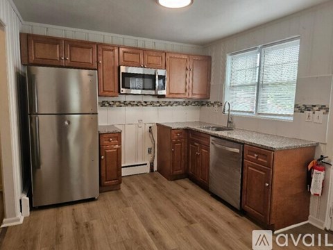 A kitchen with wooden cabinets and a stainless steel refrigerator.
