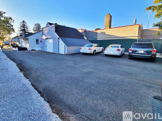 A white car is parked in front of a white building.
