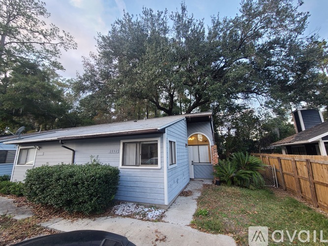 A blue house with a brown fence and trees in the background.