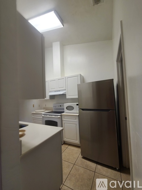 A kitchen with a stainless steel refrigerator and white cabinets.