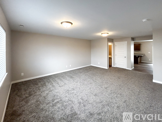 A spacious room with grey carpeting and white walls.
