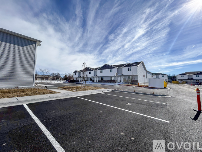 A parking lot with a building in the background and a sunny sky.