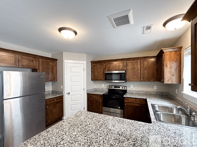 A kitchen with a granite counter top and stainless steel appliances.