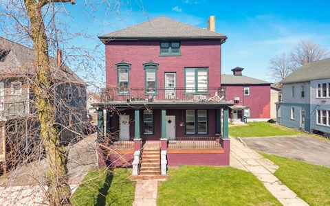 A red brick house with a green front porch.